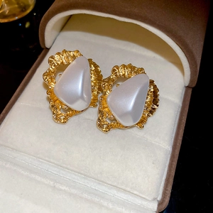 Vue détaillée des boucles d'oreilles triangulaires dorées avec incrustation de perle