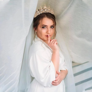 Elegant gold bridal tiara with rhinestones and pearls worn by a model in a wedding setting