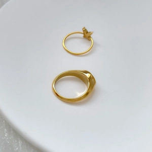 Detail of gold butterfly ring and minimalist signet ring on white ceramic tray