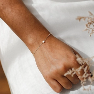 Close-up of a delicate S925 sterling silver chain bracelet with a single round white pearl