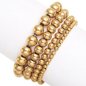 Set of four gold stainless steel beaded bracelets in different sizes on a white display stand