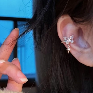 Detailed view of a sparkling zirconia butterfly ear cuff with a star dangle on a model's ear.