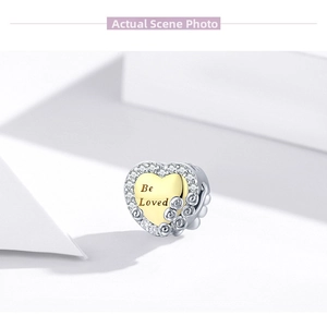 Detail of 925 silver heart charm with gold Be Loved engraving and rose embossing
