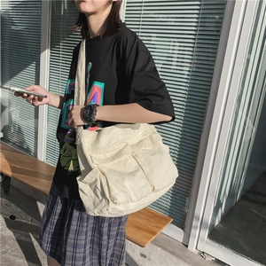 Unisex cream canvas crossbody bag with multiple pockets in casual utilitarian style