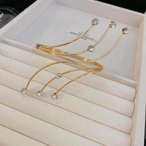 Detail of gold multi-layer wrap arm cuff featuring sparkling round crystal accents