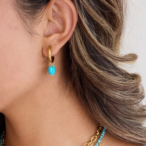 Elegant gold stainless steel hoop earrings featuring turquoise stones worn by a model