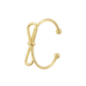 Macro detail of a golden metal bow-shaped ear cuff with smooth polished finish and round beads