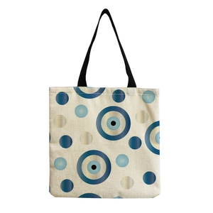 Detailed view of beige canvas tote bag with iconic blue evil eye print pattern
