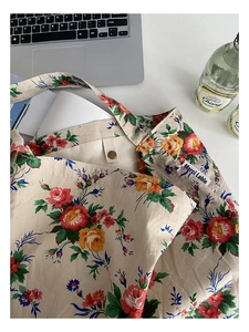 Detail view of the floral canvas tote bag featuring a metal snap button and fabric lining