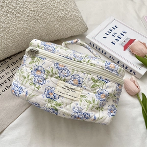 Close-up of quilted floral cosmetic bag with blue flower patterns and soft cotton texture
