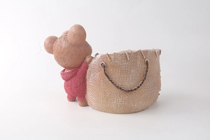 Dettaglio vaso di fiori orso in resina con felpa rossa e borsa a trama intrecciata