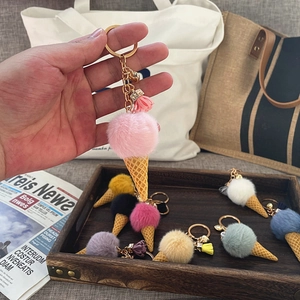 Detail view of pink plush ice cream cone keychain with gold ring and tassel charm accessory