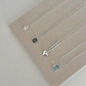 Detail view of heart pendants and pearl necklaces on a velvet jewelry display tray