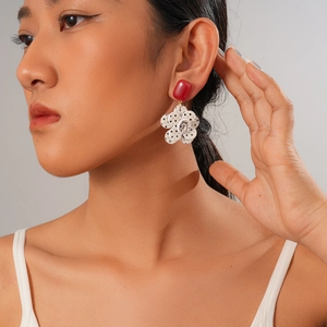 Close-up of model wearing floral acrylic earrings with red studs and black polka dots