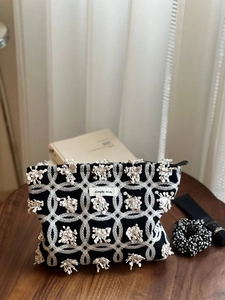 Vue détaillée d'une trousse à maquillage en toile noire avec broderie florale blanche