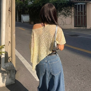 Detail of yellow knit top featuring asymmetrical cut and semi-sheer texture from behind