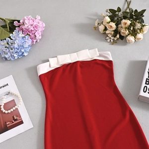 Detail of red tube dress with white bow accent and knit texture on a stylish flat lay