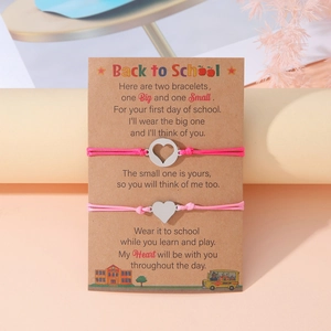 Macro di braccialetti intrecciati rosa con ciondoli a cuore su biglietto Back to School