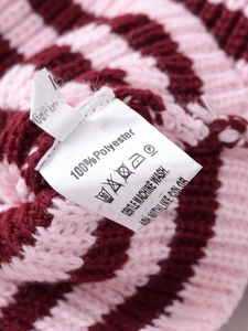 Vue détaillée de l'étiquette sur une veste en tricot à rayures roses et bordeaux 100% polyester