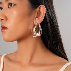 Detail of a minimalist 18K gold plated silver stud earring with abstract geometric shape