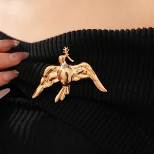 Elegant gold bird brooch with olive branch pinned on black striped knitwear