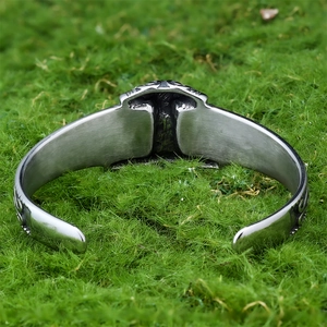 Detail of Nordic Thor hammer cuff bracelet with Celtic relief on green moss background