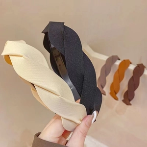 Detail shot of multi-color braided fabric headbands in beige, black, and brown tones