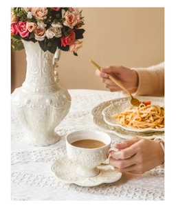 Close-up of vintage creamy ceramic coffee set with intricate embossed floral textures