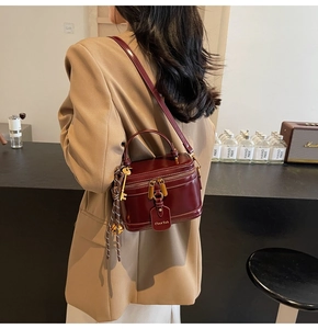 Model wearing a vintage burgundy box bag with metallic lock in a cozy cafe setting