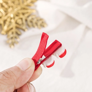 Red Christmas hair clip with cute holiday ornaments held by hand against festive background