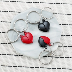 Magnetic heart couple keychains in black and red on a white ceramic tray