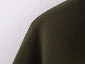 Macro shot of dark green wool coat fabric texture showing heavy-duty stitching details