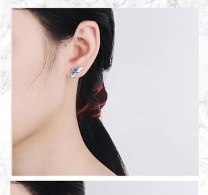 Detail of a blue enamel butterfly wing earring on model showing fine golden metallic trim