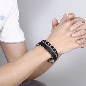 Close-up of men's double-layered black leather and beaded bracelet with silver metal accents