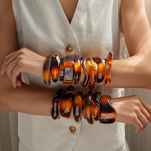 Close-up of stacked tortoiseshell resin bangles with irregular geometric shapes on a wrist