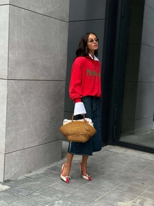 Outdoor street style shot of red half-zip sweatshirt with green letter print detail