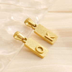 Detail of matte gold rectangular titanium steel pendants with O and K letter engravings