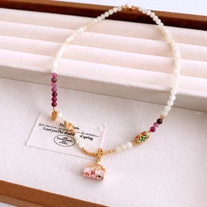 Détail du collier de perles avec pendentif sac rose et breloques émaillées en écrin