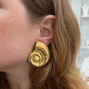 Gold-plated conch shell stud earrings on model for a chic beach vacation look