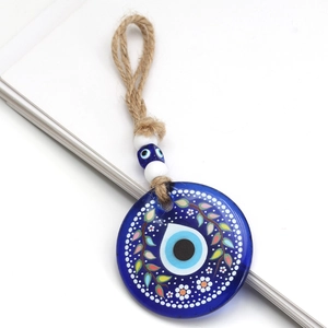 Close-up of blue glass evil eye pendant with hand-painted green leaves and jute rope