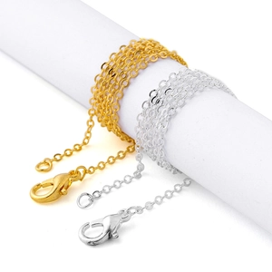 Detailed view of silver and gold link chains with lobster clasps on white cylinders