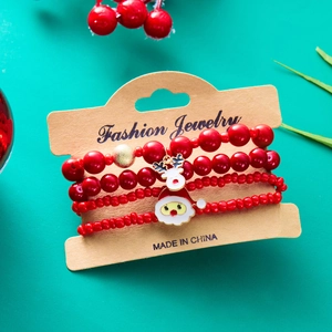 Dettaglio di quattro braccialetti natalizi con perline rosse e ciondoli a tema