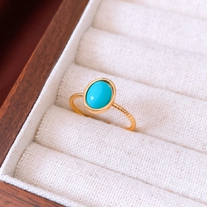 Detail of an 18k gold plated oval tiger eye stone ring set in a luxury white fabric jewelry box