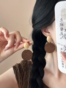 Detail of vintage round wood pendant earrings with matte gold oval metal accents