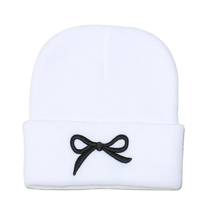 Détail d'un bonnet en tricot blanc avec broderie nœud noir et texture de maille fine