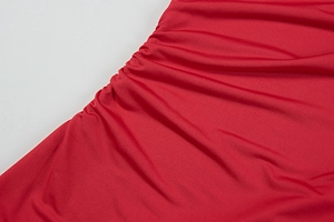 Detailed close-up of vibrant red ruched fabric showing texture and stitching on the dress