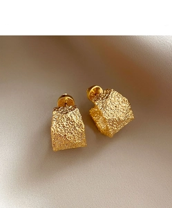 Macro shot of gold-tone geometric C-shape earrings with a hammered textured finish