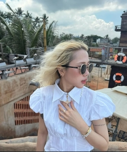Close-up of white puff sleeve polo top styled with starfish jewelry on tropical beach