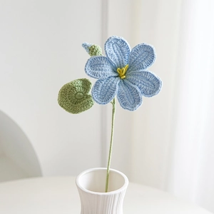 Dettaglio di fiore blu all'uncinetto fatto a mano con stame giallo e foglia verde