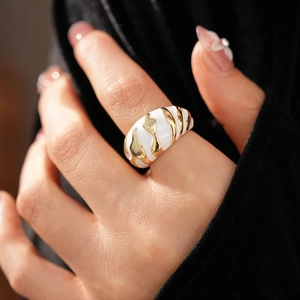 Close-up of vintage gold wave ring with white enamel detail on model's finger